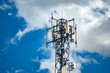 © ismailgazel - Telecommunications cell tower under blue sky with clouds. Low angle view of a modern telecommunication antenna tower showcasing wireless technology against a bright blue sky with puffy white clouds.