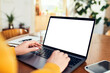 © baranq - Woman typing on laptop with blank white screen at home desk