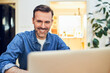 © baranq - Man smiling while using laptop at home