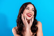 © deagreez - Smiling woman portrait with red lipstick and glamorous jewelry against bright blue background, joyful beauty and fashion look