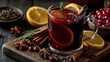 © Irina Ivanova - A cozy glass of mulled wine on a wooden board, garnished with orange slices, cinnamon sticks, star anise, and fresh rosemary in a warm setting.