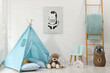 © New Africa - Wigwam, toys, small chair and pillows near white wall in child's room