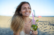 © SISMIZ - Smiling woman with a refreshing cocktail on a sunny beach day