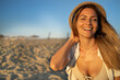 © SISMIZ - Joyful woman with straw hat laughing on a sunny beach at golden hour