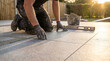 © ViskBx - Professional paver laying stone tiles on a patio in a garden setting at sunset, focusing on the precision of the installation process