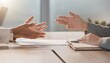 © andre - Two business people discuss documents and ideas across a wooden office desk with hands extended