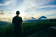 © Atlas - Person watches sunset over mountains and clouds in Bali