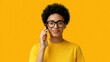 © ชลธิชา สว่างวงค์ - Smiling young person with curly hair and glasses having phone conversation on vibrant yellow background