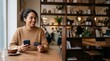 © Николай Срибяник - Smiling diverse woman holding credit card and smartphone in a modern cafe.