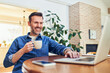© baranq - Man drinking coffee and working on laptop at home