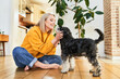 © baranq - Woman sitting on floor petting miniature schnauzer at home