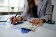 © Phimwilai - Businesswoman calculating finances working on financial document at desk