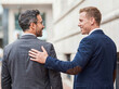 © Athena Studio - Two professional male colleagues sharing a moment of encouragement and understanding in a formal urban business setting.