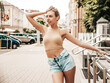 © halayalex - Portrait of beautiful smiling model dressed in summer hipster  jeans shorts. Trendy female posing in the street background. Funny and positive woman having fun in sunglasses. Playing with her hair