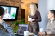 © Ina - Business presentation during office meeting with remote participant on screen. Modern hybrid work, teamwork and online collaboration concept in professional environment.