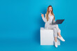 © deagreez - Smiling businesswoman with laptop pointing to space for text on blue background, casual modern professional portrait
