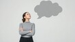 © olga_demina - Businesswoman is standing with her arms crossed, looking up at a gray speech bubble, contemplating a question or message, embodying the concepts of communication and thought