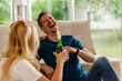 © milanmarkovic78 - Friends Enjoy a Fun Time Laughing and Sharing Drinks Inside a Cozy Living Room During a Sunny Afternoon Gathering
