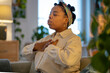 © ingoodtime - Mindful break of black woman using conscious breathing technique to calm anxiety and restore emotional balance at home. Self regulation, coping with stress, mindfulness, mental health, wellness habits