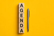 © Ishan - Agenda planning concept with wooden alphabet blocks and pen representing organized scheduling productivity and effective business management practices today