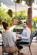 © Jelena - Couple sitting outdoors talking and smiling in garden
