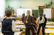 © Alina - Elementary school children stand at desks during an interactive lesson for a group physical break activity that encourages movement and focus in a modern classroom setting for pupils