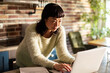 © Davor - Focused woman working on laptop in a home kitchen