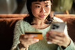 © Davor - Woman using credit card and smartphone at home
