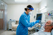 © Tatiana Selinger - A professional healthcare worker in personal protective equipment monitoring a patient in a critical care hospital setting