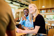 © we.bond.creations - Young diverse business colleagues meeting and discussing ideas in a comfortable, modern co-working space, smiling and happy