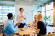 © we.bond.creations - Group of diverse business professionals applauding and showing appreciation to a happy female team member during an office meeting