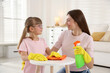 © New Africa - Spring cleaning. Happy mother and her daughter wiping dust from table together at home