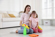 © New Africa - Spring cleaning. Happy mother and her daughter with detergent sitting on floor at home
