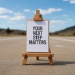 © Pixzens Ars - Inspirational motivational quote on whiteboard on wooden easel outdoors  your next step matters