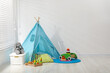 © New Africa - Wigwam, toys and pillows near white wall in child's room, space for text
