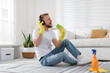© New Africa - Spring cleaning. Happy man with brush and headphones having fun at home