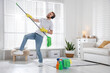 © New Africa - Spring cleaning. Man having fun and tidying up floor with mop at home