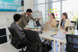 © MrAshi - A group of Asian business leaders from various nationalities collaborate in a modern office conference room, discussing project analysis charts during a workplace meeting.