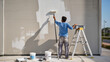 © Jakub - Fresh White Coat​Wall Painting Process​Exterior Wall Renovation​Worker with Paint Roller​Sunny Day Renovation​Painting the Facade​Home Improvement Project​Roller and Extension Pole