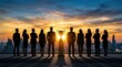 © Supernova - Successful business team standing with trophy silhouetted against city skyline at sunset