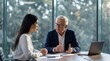 © 5 Grace Media - Two diverse business professionals engaged in serious discussion during a meeting in a modern office with large windows.