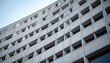 © putri - Modern brutalist concrete building facade with rectangular windows.