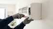 © Nazlykhan - Technician repairing air conditioner with screwdriver. Man fixing home climate control system. Professional HVAC maintenance and installation service. Equipment service and repair concept.
