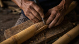 Closeup of hands carving intricate designs into bamboo stalk.