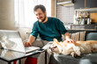 © Westend61 - Portrait of smiling man sitting on couch at home using laptop