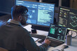 © DragonImages - Young adult Caucasian man monitoring code and network dashboards across multiple screens, analyzing cybersecurity data. Ideal for IT security, software development, data protection marketing