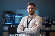 © DragonImages - Portrait of Caucasian young adult businessman standing with crossed arms in office, looking at camera and conveying confidence. Ideal for leadership, corporate profile, recruitment marketing