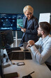 © DragonImages - Vertical shot of Caucasian businesswoman discussing data dashboard with Caucasian businessman in office, reviewing analytics on screens. Ideal for teamwork, strategy, tech consulting