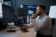 © DragonImages - Caucasian young adult man analyzing cybersecurity data on multiple monitors in office, monitoring code and dashboards. Ideal for IT security, data analytics, tech workplace marketing
