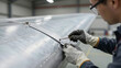 © Lubov - Aerospace engineer inspecting an aircraft wing panel in a hangar. Professional technician performing maintenance on a metal plane part for safety and quality